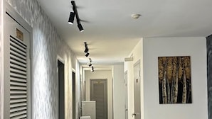 A modern hallway with a tiled floor, a painting on the wall, and a ceiling light fixture. - Homigo - PWTC (Kuala Lumpur)