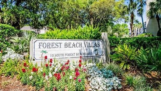 Een bord met 'Forest Beach Villas', een palmpijl en een klein palmbeeldje.