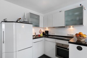 Een moderne keuken met witte kasten, een inbouwoven en een koffiezetapparaat op het aanrecht.