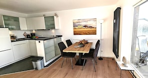 Uma cozinha moderna com armários brancos, uma mesa de jantar de madeira e uma janela grande.