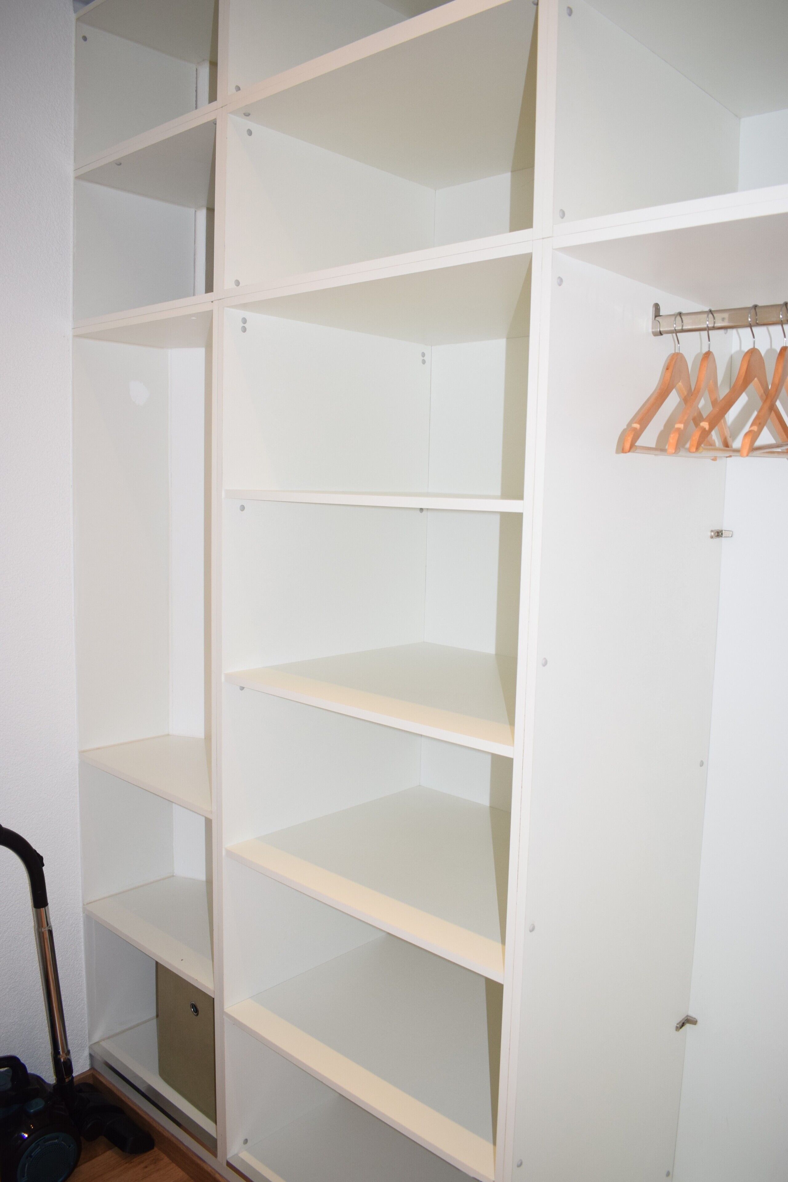 Un placard blanc avec plusieurs étagères et une tringle pour suspendre les vêtements.