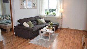 Een woonkamer met een grijze bank, een witte salontafel en een lamp.