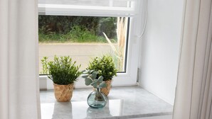Een raam met zonwering, een radiator en twee plantenpotten op de vensterbank.