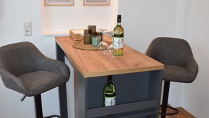 Een kleine bar met twee barkrukken, een houten tafel en twee lijstjes aan de muur.