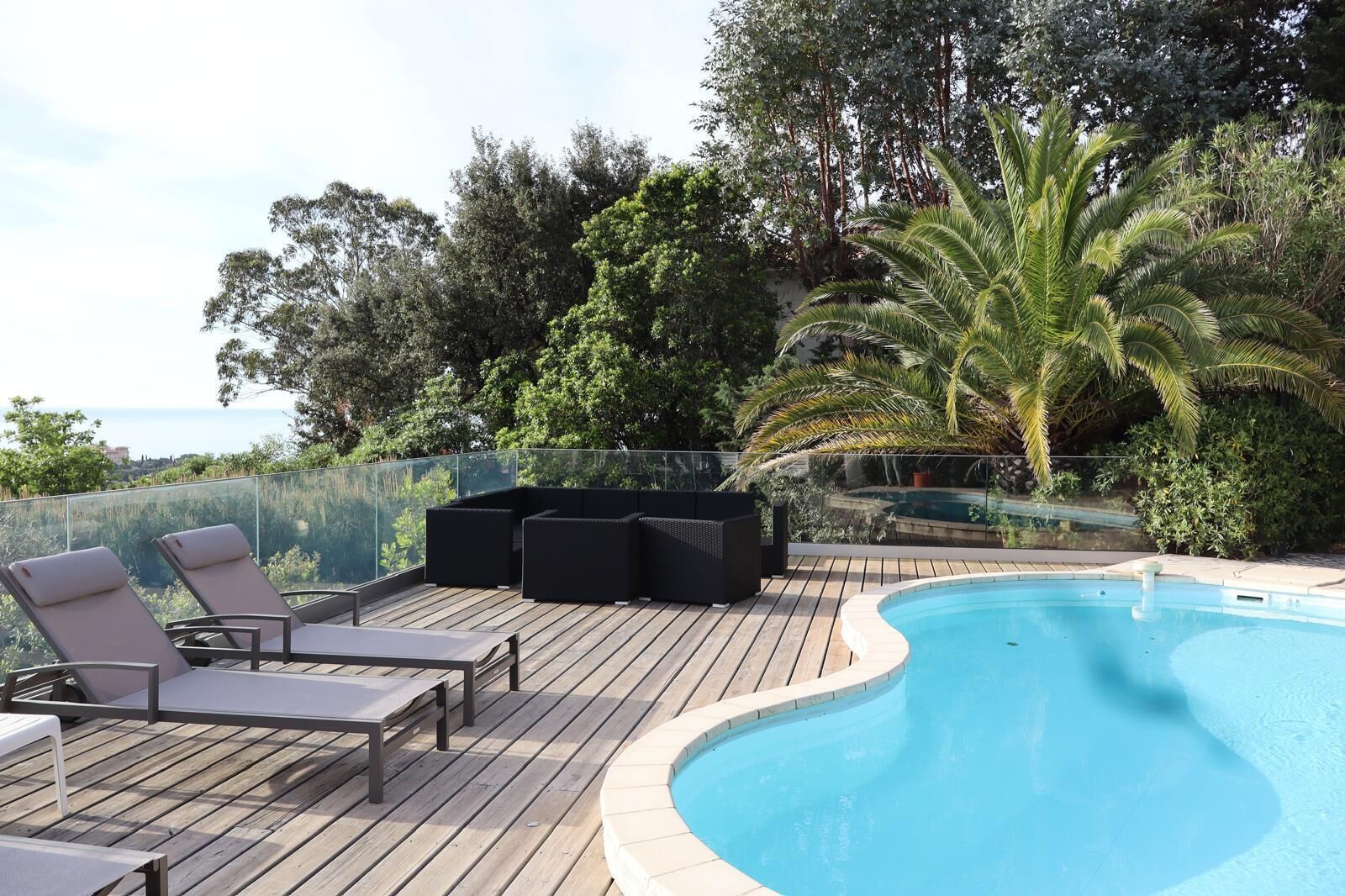 A poolside area with lounge chairs and a wooden deck.