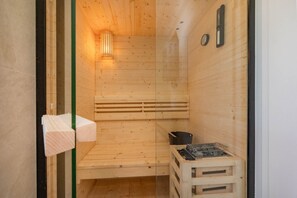 A sauna with wooden walls and a bench, a towel rack, and a sauna heater. - Cozy vacation home "Domizil zum Lerchengrund 03" in Ückeritz close to the beach (Ückeritz)