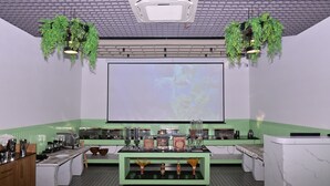 Una cocina moderna con una isla grande, detalles en verde y plantas colgantes.