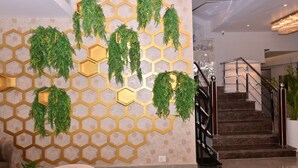 Un interior moderno con una pared de patrón hexagonal, una escalera y una planta en maceta.