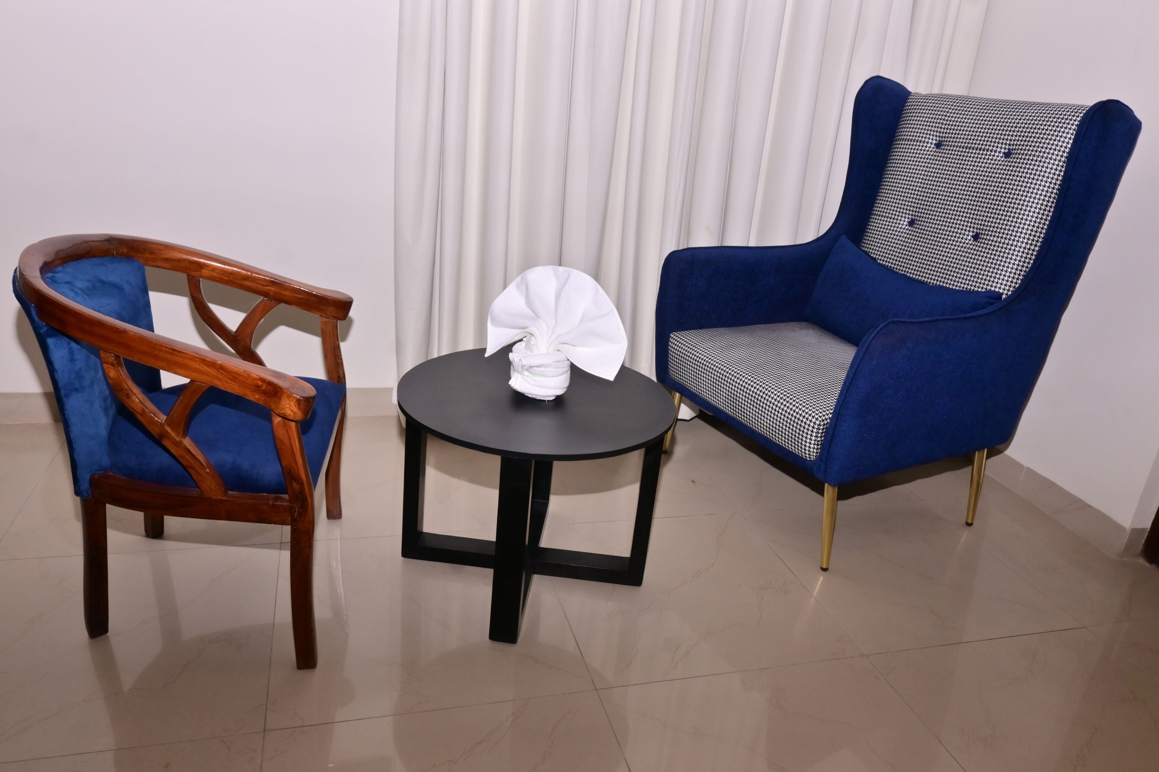 Ein Zimmer mit einem Holzhocker, einem runden Tisch und einem blauen Sessel.