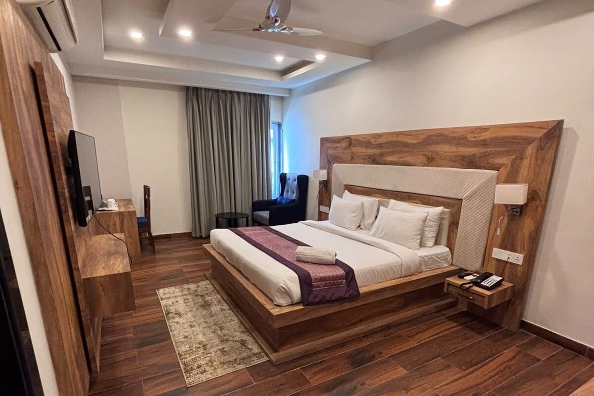 Quarto de hotel moderno com uma cama grande, uma escrivaninha, uma cadeira e uma televisão.