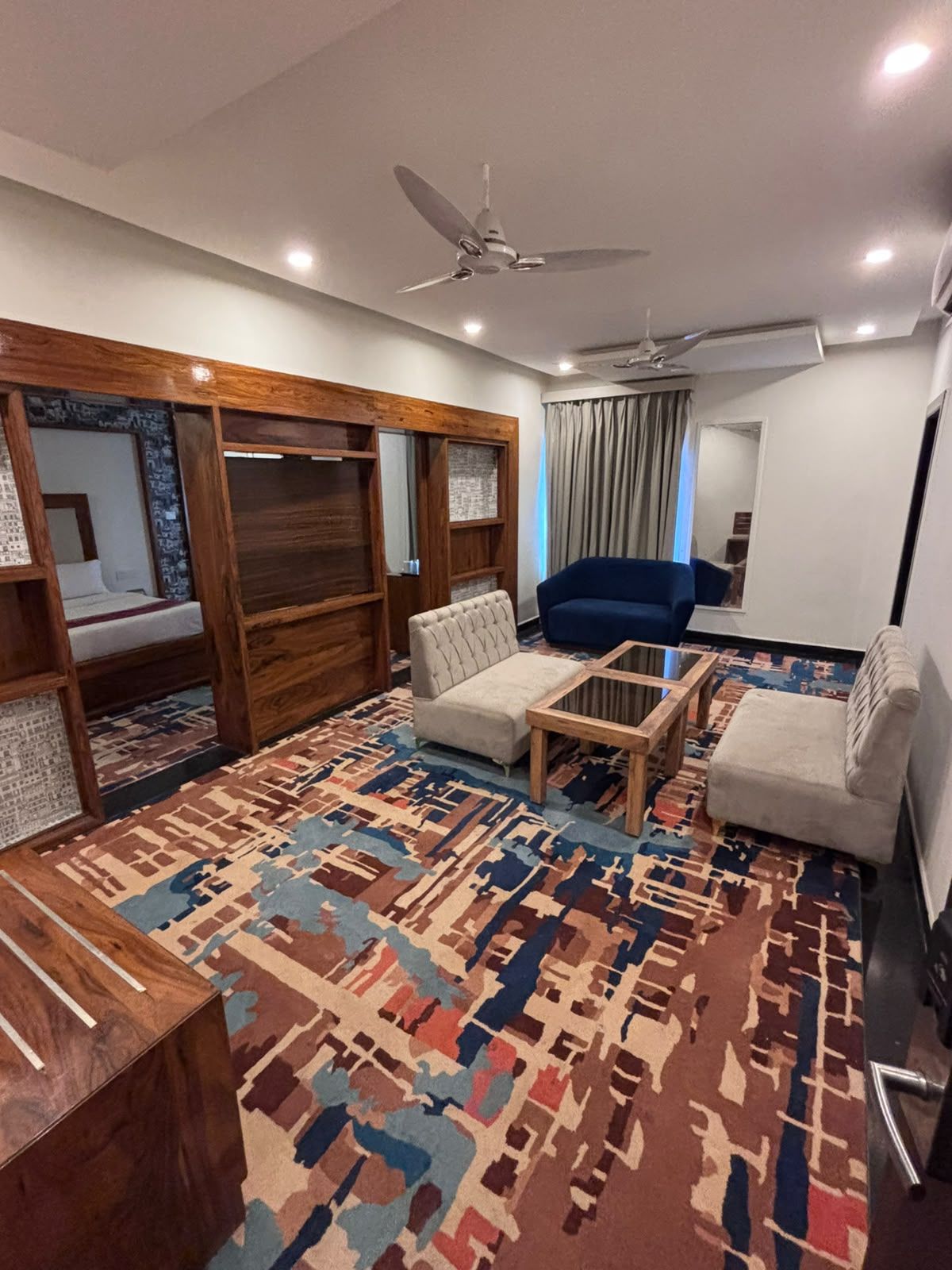 A modern living room with a sofa, armchairs, a coffee table, and a patterned rug.
