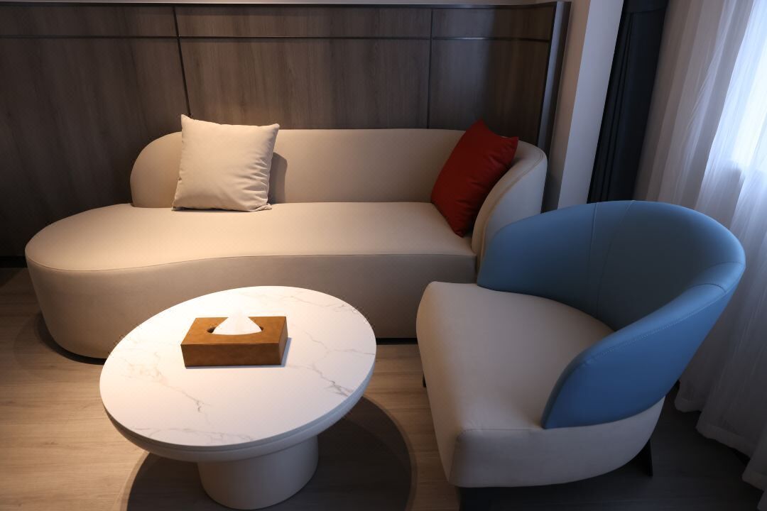 A modern living room with a sofa, a blue armchair, and a marble coffee table.