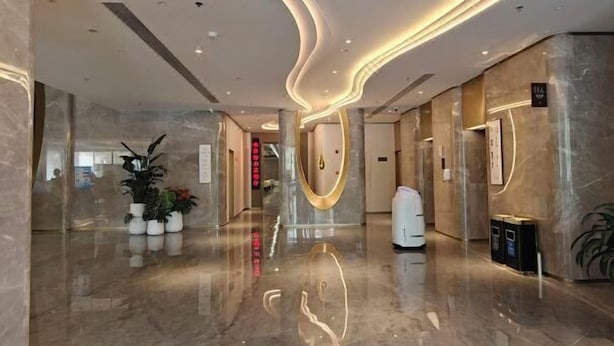 A modern hotel lobby with marble flooring, a curved ceiling design, and a reception desk. - Golden Panda Hotel (Beijing)