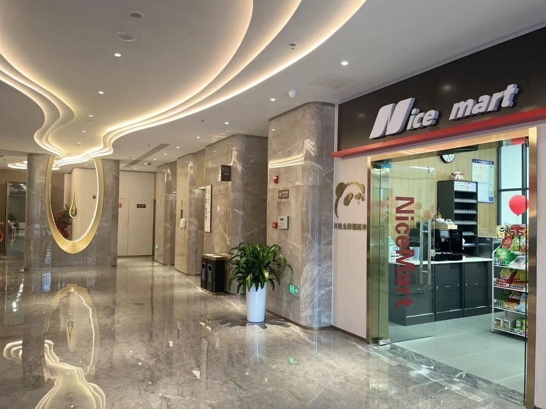 A modern interior with a 'Nice mart' store, marble flooring, and a potted plant.