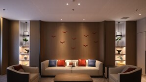A modern living room with a sofa set, two side chairs, a coffee table, and decorative wall art. - Golden Panda Hotel (Beijing)