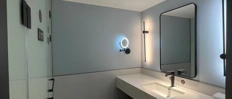 Un baño moderno con un espejo grande, un lavabo y un perchero para toallas.