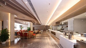 A modern dining area with a long counter, multiple tables, and chairs. - Golden Panda Hotel (Beijing)