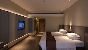 A modern hotel room with a large bed, bedside tables, a flat-screen TV, and a hallway leading to another room. - Golden Panda Hotel (Beijing)