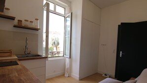 Une petite cuisine moderne, dotée d’une fenêtre, d’un comptoir en bois et d’une porte noire.