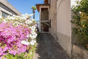Une ruelle étroite, bordée d’un côté par un mur de pierre et de l’autre par l’entrée d’un immeuble.