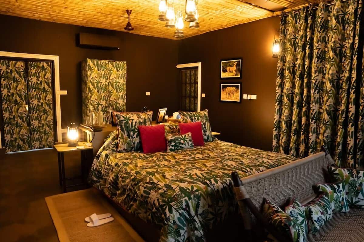 Una camera da letto con un letto, un comodino, una lampada, uno specchio e tende a tema tropicale.