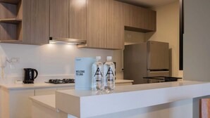 Una cocina moderna con armarios de madera, encimera blanca y refrigerador de acero inoxidable.