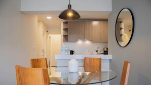 Una cocina moderna con armarios de madera, una mesa de comedor de vidrio y una lámpara colgante.