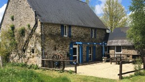 Ein Steinhaus mit traditionellem Design, das ein großes Holzrad und eine überdachte Veranda zeigt.