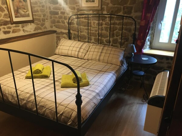 A single bed with a metal frame, a small table, and a heater.