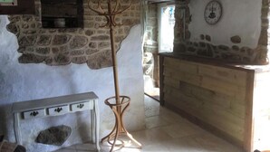 Ein rustikales Interieur mit Steinwänden, einer Holzbank, einem Kamin und einer Wanduhr.