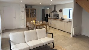 Una cocina moderna con armarios blancos, un comedor con mesa y sillas, y un sofá en la sala de estar.