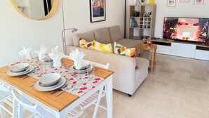 Un salon moderne comprenant un coin repas, un canapé, un téléviseur et une bibliothèque.