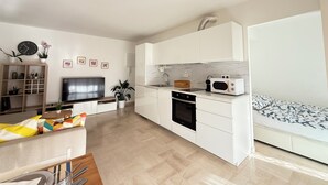 Un appartement moderne comprenant un salon, une cuisine et une petite chambre.
