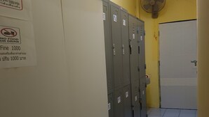 Un pasillo con casilleros, un ventilador y una puerta.