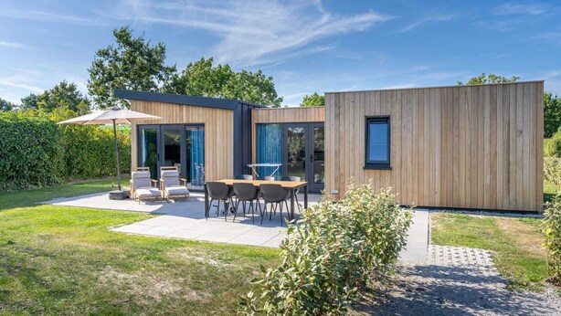 A modern house with a patio, outdoor seating, and a wooden exterior. - Welcome to Muralt 110, a modern chalet with everything for a carefree stay. Enjoy the cozy living ro (Scharendijke)