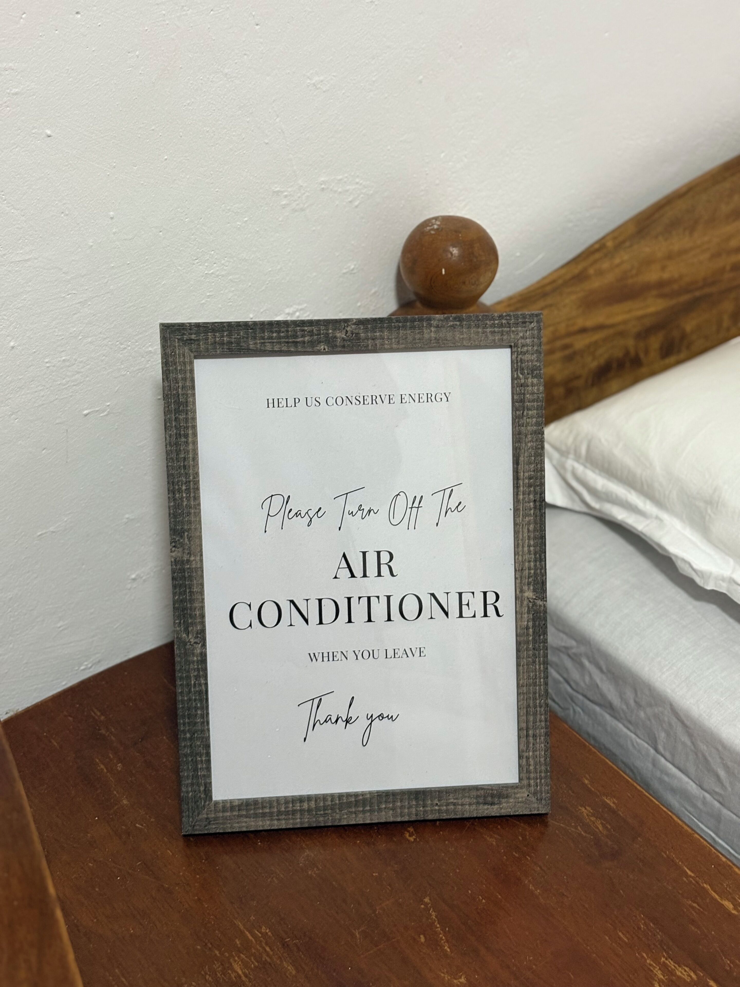 Une pancarte encadrée, posée sur la table de chevet, rappelle de bien éteindre la climatisation avant de quitter la pièce.