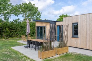 A modern outdoor patio with a wooden table and chairs, a pergola, and wooden planters. - Welcome to Muralt 111, a modern chalet with everything for a carefree stay. Enjoy the cozy living ro (Scharendijke)