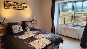Een slaapkamer met een groot bed, een hoofdbord met planken, een raam met zonwering en een schilderij aan de muur.