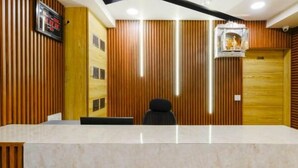 A reception area with a marble counter, wooden paneling, and a digital clock.