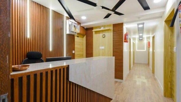 A reception area with a wooden reception desk, a black office chair, and a ceiling fan.