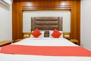 Una habitación de hotel con una cama grande, un cabecero de madera y dos mesitas de noche.