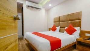 A hotel room with a wooden bed frame, white bedding, and red accents.