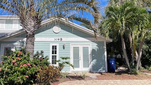 Une maison de plain-pied à la façade bleu clair, avec une porte blanche et une boîte aux lettres.