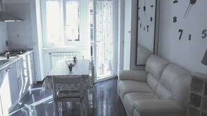 Eine moderne Küche mit Essbereich, einer Couch und einer Wanduhr.