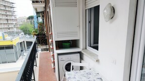Ein Balkon mit Waschmaschine, Tisch und Stühlen.