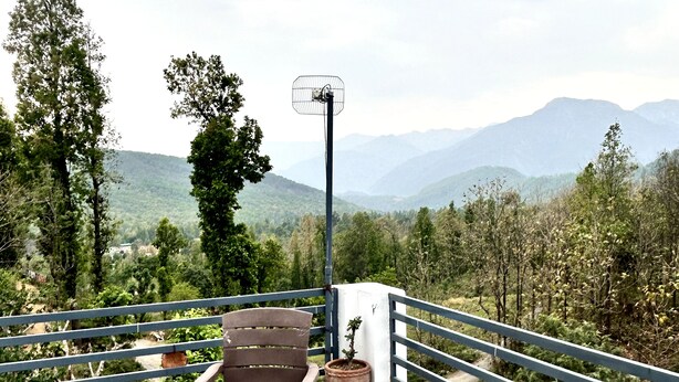 Une terrasse avec une table et des chaises, un pot de fleurs et une vue sur les montagnes.