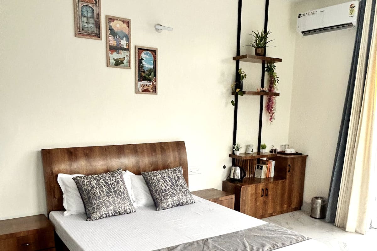 A bedroom with a wooden bed, a marble floor, a patterned rug, a small cabinet, and wall-mounted shelves with plants.