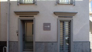 Fachada de edificio con puerta y ventana, una placa con el número 22, y una barandilla metálica sobre la puerta.