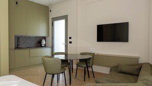 Una sala moderna con sofá, una mesa de comedor con sillas y una zona de cocina con armarios y encimera.