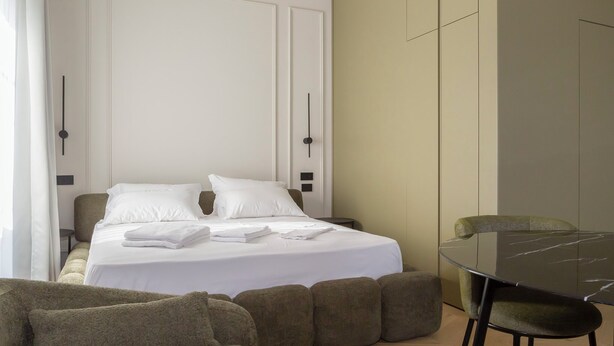 Una habitación de hotel moderna con una cama bien hecha, una mesa de comedor y un sofá.